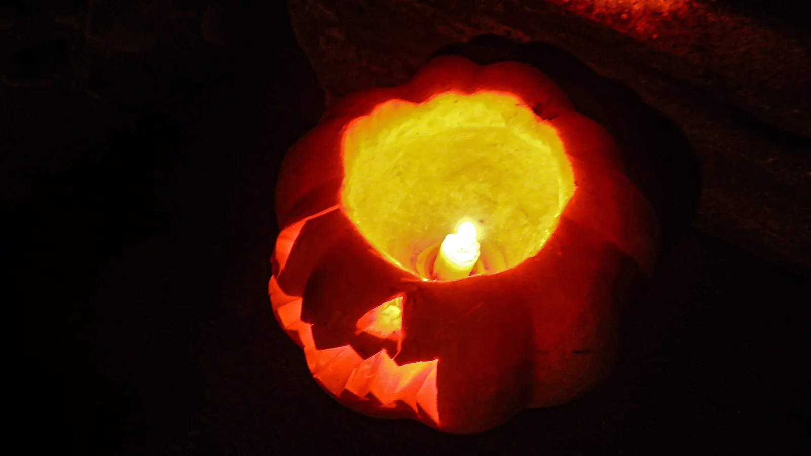 Αναμμένη κολοκύθα Halloween με κερί στο σκοτάδι